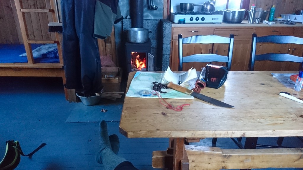 Inside of Skarvassbu cabin with a stove and a table with a knife and snow goggles