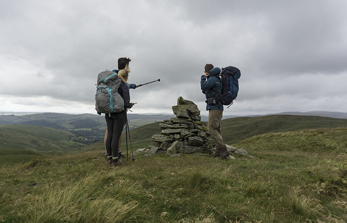 3 people pointing out features from the top of Garn Gron in the Cambrian mountains